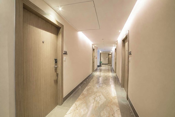 Pasillo de hotel con puertas numeradas 106 y 107, suelo de mármol e iluminación empotrada.
