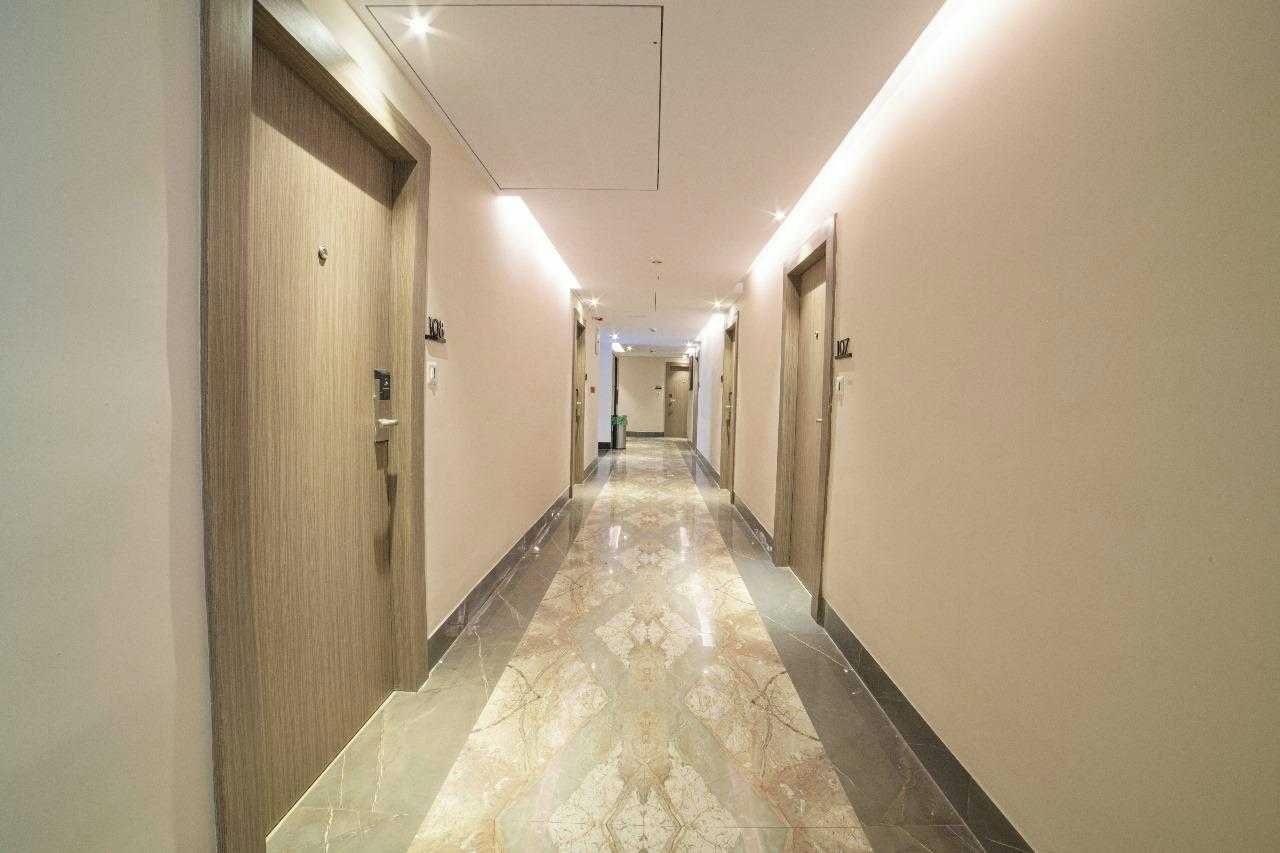 Un pasillo de hotel con puertas a ambos lados, suelo de mármol e iluminación en el techo.