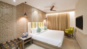 A hotel room with a bed, bedside table, chair, and a TV mounted on the wall. - Palette Hotel by CheckIn, Visakhapatnam (Visakhapatnam)
