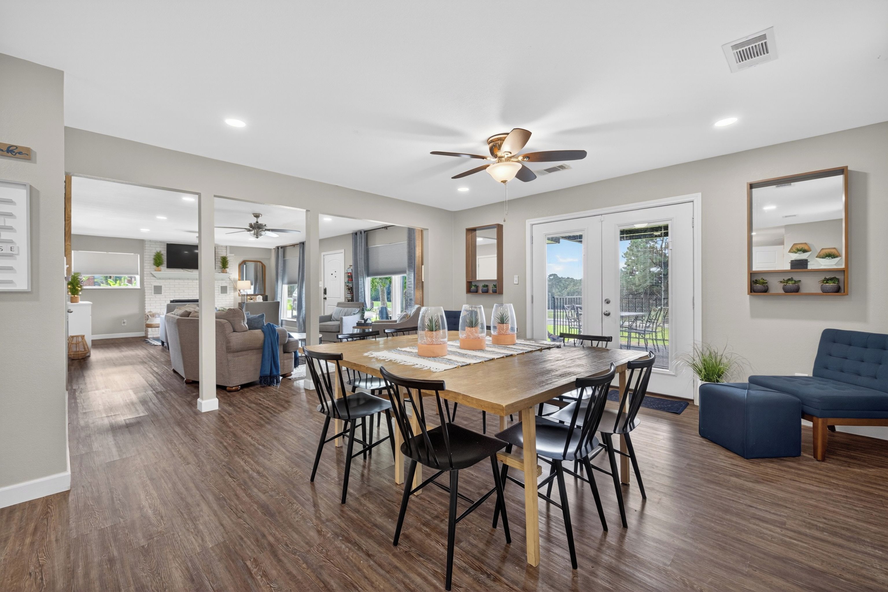 A spacious living area with a wooden dining table, black chairs, and a blue sofa.