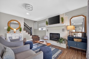 A modern living room with a fireplace, a flat-screen TV, and a staircase. - Lake Degray Golf-Course and Lake Retreat/Covered Patio 4 Bedrooms 3 Full Bath (Bismarck)