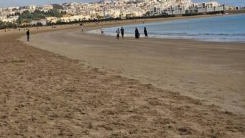 Une vaste plage de sable offrant une vue dégagée sur une ville côtière en arrière-plan.