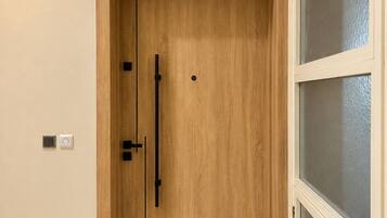 Une porte en bois portant le numéro 23, un interphone et un clavier à code fixé au mur.