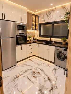A modern kitchen with stainless steel appliances, marble flooring, and a built-in oven.