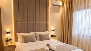 Una camera da letto moderna con un grande letto, una testiera con pannelli verticali, comodini con lampade e una finestra con tende.