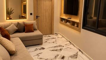 Un salon moderne avec un canapé, un téléviseur fixé au mur et une porte en bois.