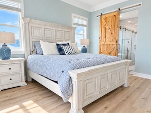 A bedroom with a large bed, two bedside tables, a wooden door, and a view of the outdoors. - Beachfront, Private Elevator, Hot Tub, Sleeps 24 (Freeport)