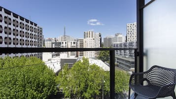 Ein Balkon mit Blick auf eine Stadtansicht, ein Metallstuhl und ein Gebäude mit einer markanten Fassade.
