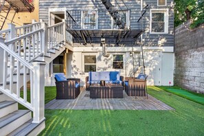 A two-story house with a patio area featuring wicker furniture and a small lawn. - Classic 3 bedroom Hoboken Retreat  Private Backyard (Hoboken)