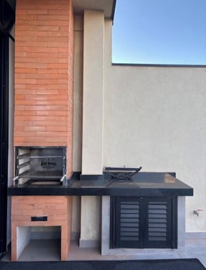 An outdoor kitchen with a brick oven, a gas stove, and a built-in sink.