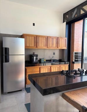 A modern kitchen with stainless steel appliances, wooden cabinets, and a black countertop island.