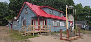A two-story building with a red roof and a porch. - Head on up to da U.P. for a naturally beautiful getaway.  Pet Friendly! (Big Bay)