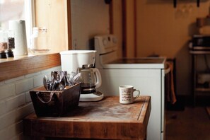 En köksbänk med en kaffebryggare, en mugg och ett förvaringsställ för köksredskap.