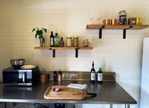 A kitchen with a microwave, cutting board, and various food items on shelves. - Head on up to da U.P. for a naturally beautiful getaway.  Pet Friendly! (Big Bay)