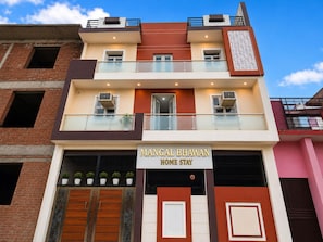 Un edificio de varios pisos con un letrero que dice 'Mangal Bhawan Home Stay'.