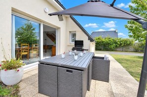An outdoor patio with a dining table, chairs, and a grill. - Ker-Nochus - PLURIEN (PLURIEN)