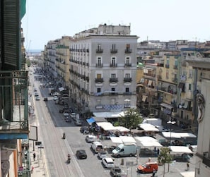 A street view with buildings, parked cars, and outdoor seating areas. - Keira house Napoli CUP (Naples)
