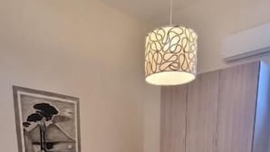 Un lit bien fait, avec une tête de lit, un luminaire suspendu et un tableau encadré accroché au mur.