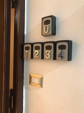 A wall-mounted number keypad with numbers 0 to 4 and a light switch below it. - Keira house Napoli CUP (Naples)
