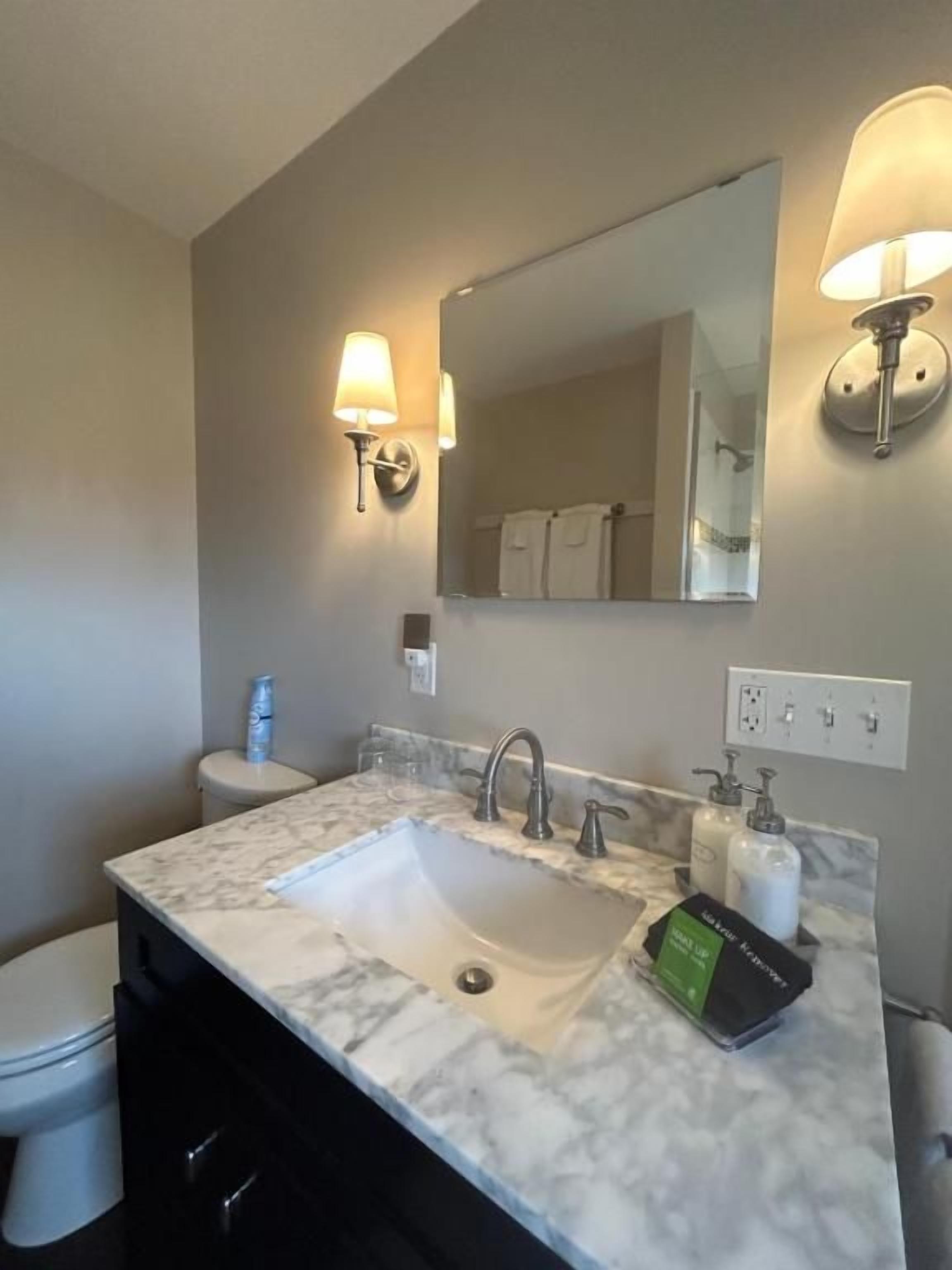 A bathroom with a marble sink, a mirror, a towel rack, and a toilet.