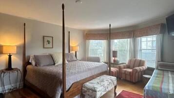 A bedroom with a four-poster bed, a bench, a chair, and a small table.