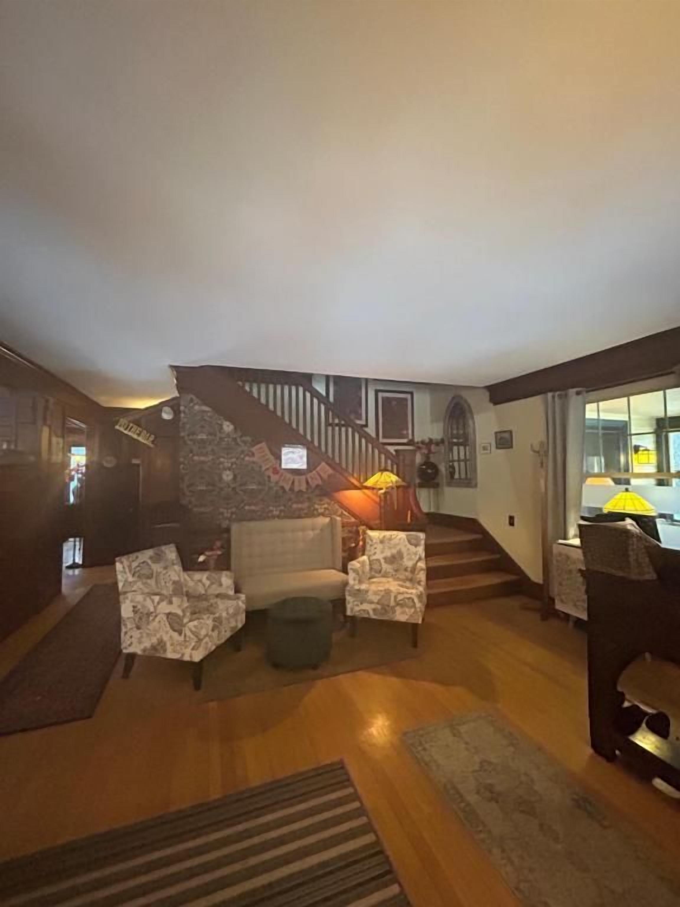 A spacious living room with a staircase leading to an upper level, a fireplace, and a piano.
