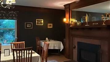 A dining area with a table set for four, a fireplace, and a large mirror above it.