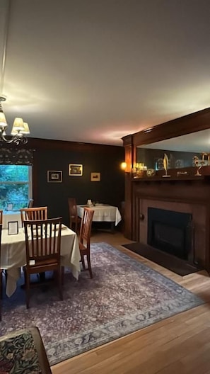 Uma sala de jantar com mesa posta para quatro pessoas, lareira e um espelho grande acima.