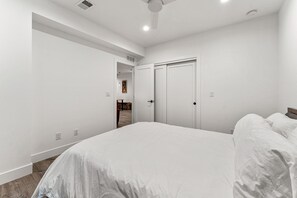 A bedroom with a large bed, white walls, and a door leading to another room. - 2 bed, 1 bath Basement Apt. with W/D in Custom Home and 1 Garage Parking Space (Denver)