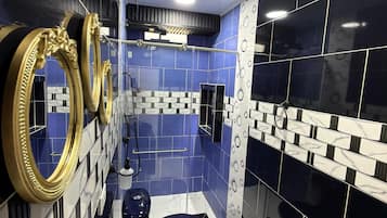 A modern bathroom with blue and black tiles, a gold-framed mirror, and a black toilet.