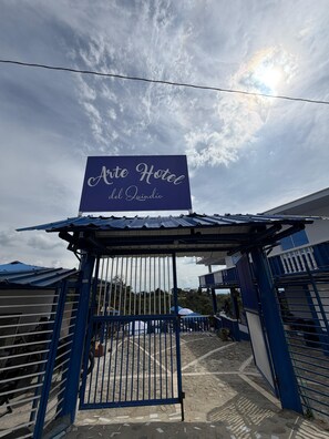A hotel entrance with a sign reading 'Ate Hotel del Quindio' and a gated entrance.