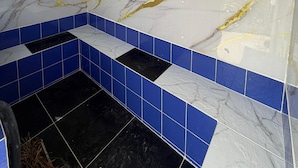 A bathroom with a white marble wall, blue tiles, and a black floor. - Artehotel del Quindío  (Filandia)