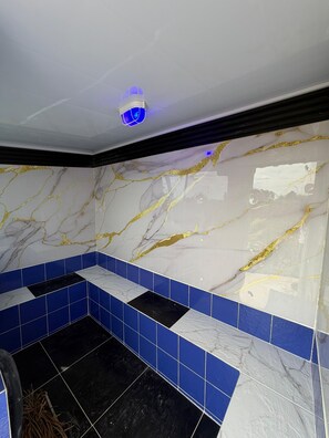 A bathroom with a white marble wall, blue tiles, and a black floor. - Artehotel del Quindío  (Filandia)