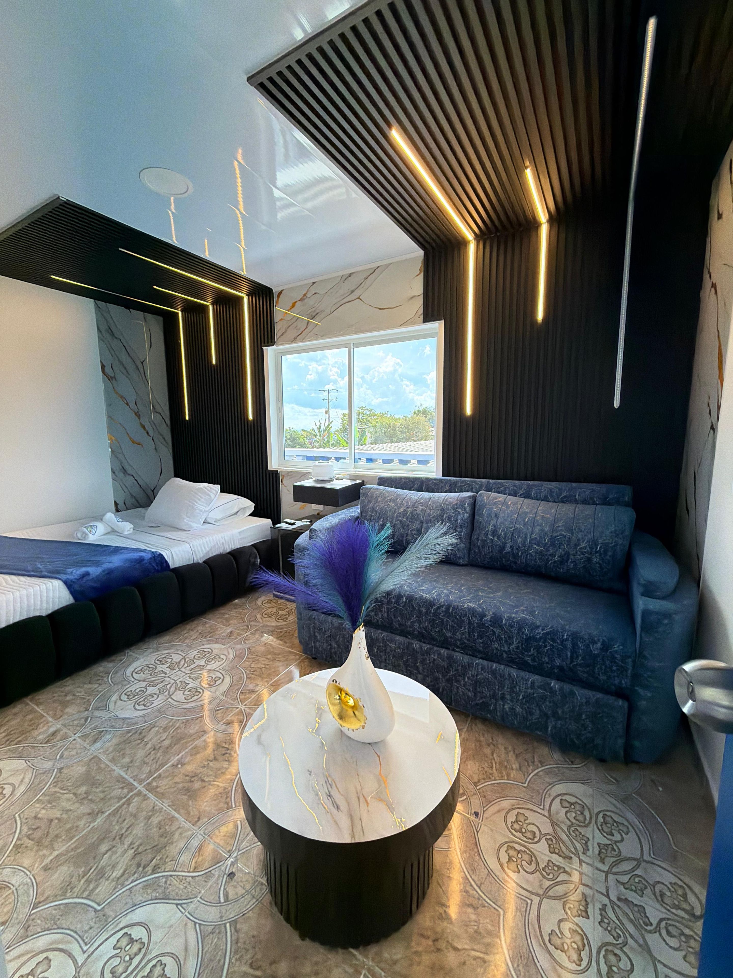 A modern living room with a bed, sofa, and a decorative vase on a coffee table.