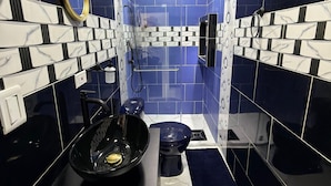 A bathroom with blue and white tiles, a black sink, and a toilet. - Artehotel del Quindío  (Filandia)