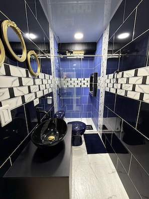 A bathroom with blue and white tiles, a black sink, and a toilet. - Artehotel del Quindío  (Filandia)