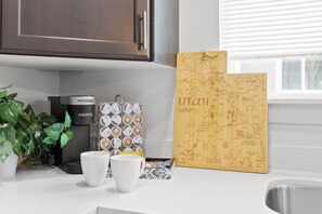 Eine Küchenarbeitsplatte mit einer Keurig-Kaffeemaschine, zwei weißen Tassen, einem Kaffee-Pod-Halter und einer Karte vom Bundesstaat Utah.
