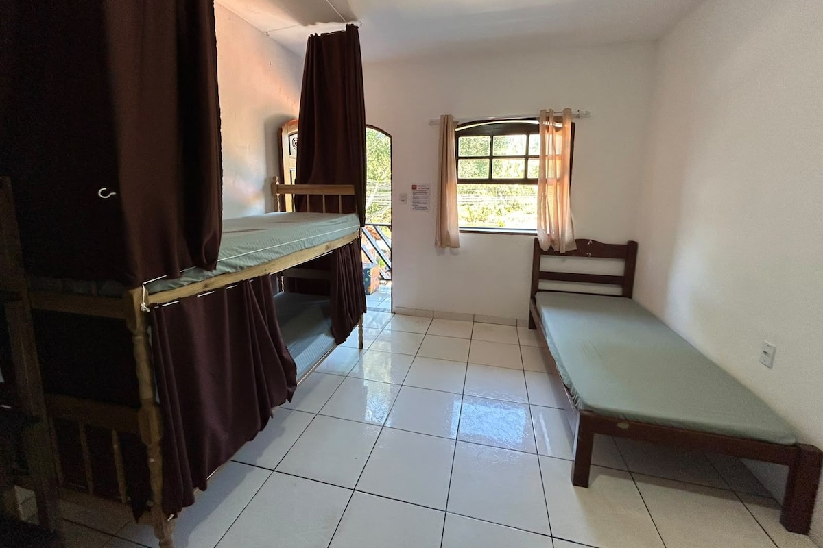 Una camera del dormitorio con letti a castello, una finestra con tende e un pavimento piastrellato.