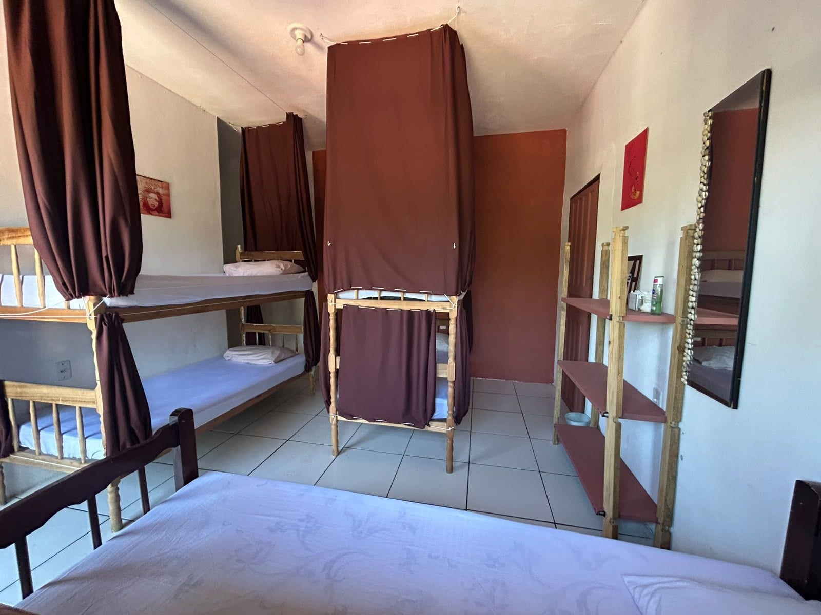 Una habitació de dormitori amb lliteres, un mirall i una prestatgeria amb articles de tocador.