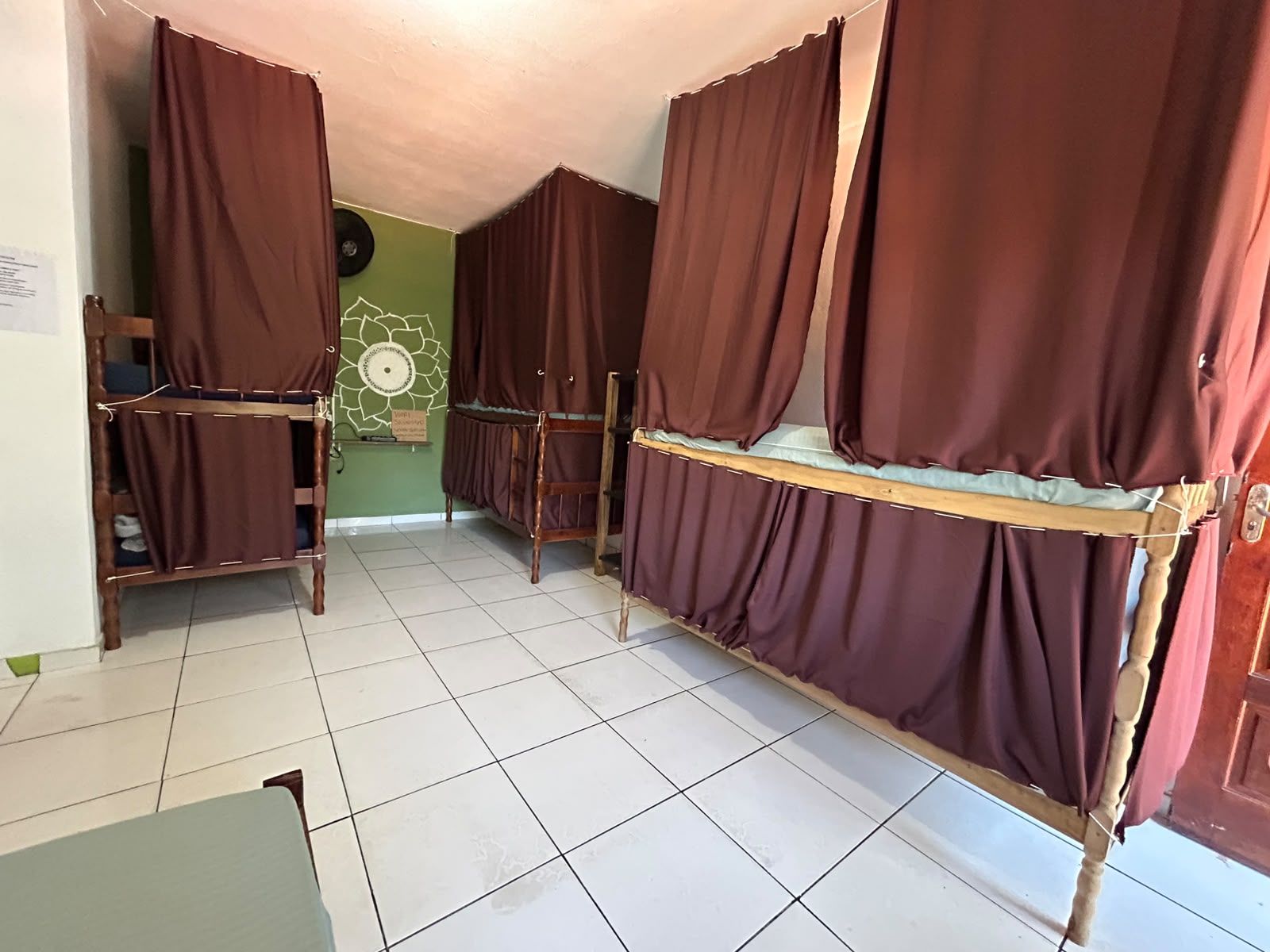 Ein Zimmer mit Etagenbetten, einer grünen Wand, einer Wanddekoration und einem Fliesenboden.