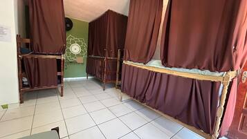Ein Zimmer mit Etagenbetten, einer grünen Wand, einer Wanddekoration und einem Fliesenboden.