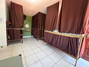 A room with bunk beds, a green wall, a decorative wall piece, and a tiled floor.