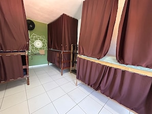 A room with bunk beds, a green wall, and a tiled floor.