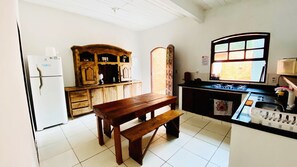 A kitchen with a wooden table, a refrigerator, and a window.