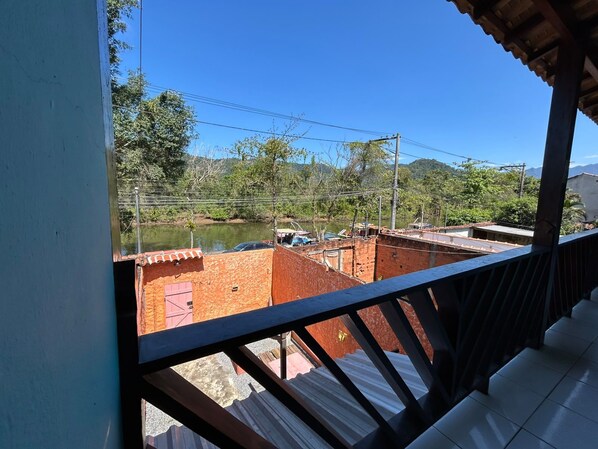 A balcony with a view of a river, a bridge, and a hilly landscape.