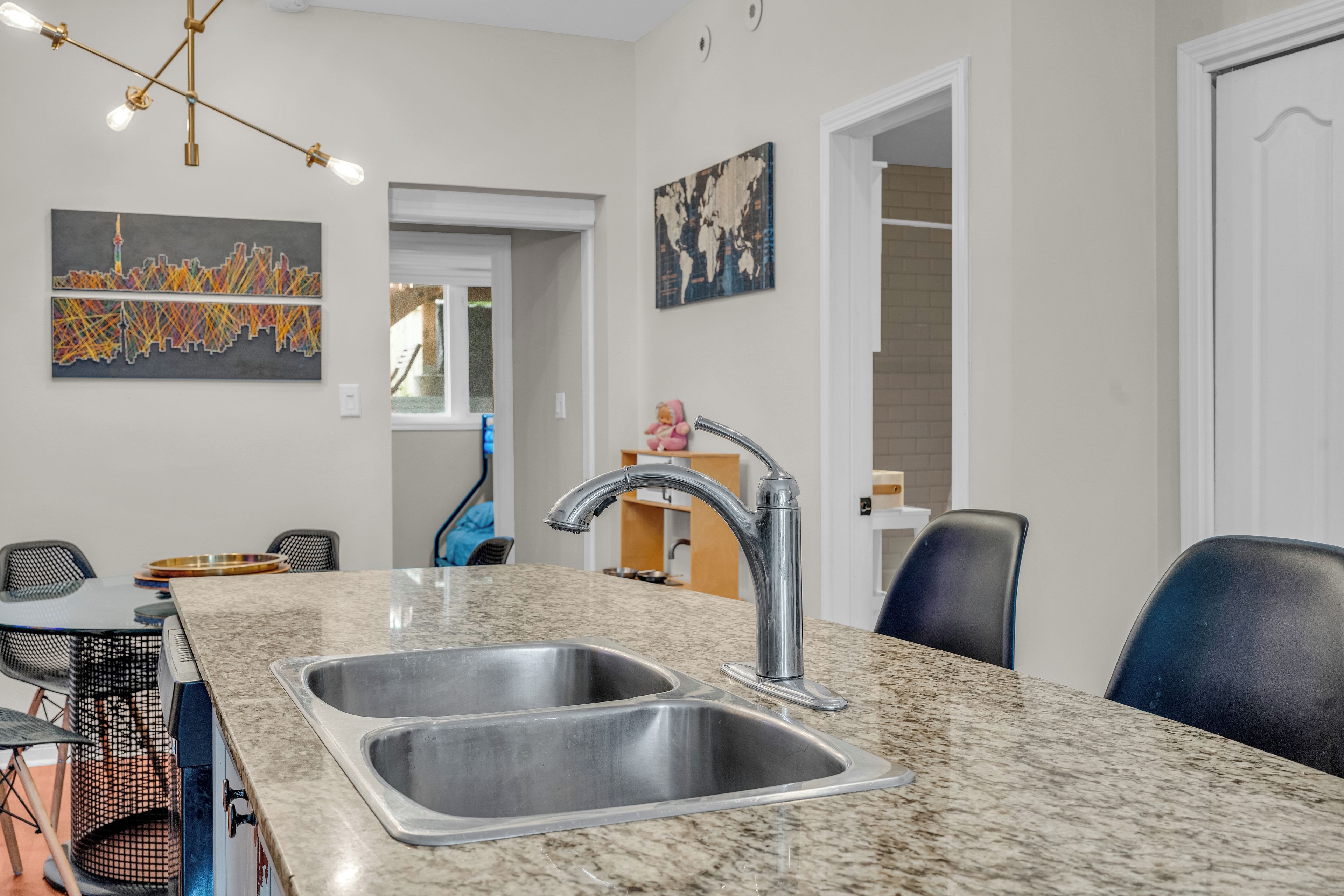 A modern kitchen with a granite countertop, stainless steel sink, and a single faucet.