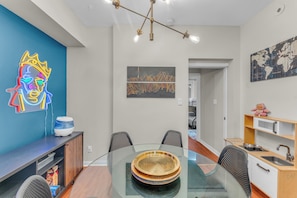 A modern dining area with a glass table, black and white chairs, a neon artwork, and a world map on the wall. - 2 BR Townhouse with Patio Terrace (Toronto)