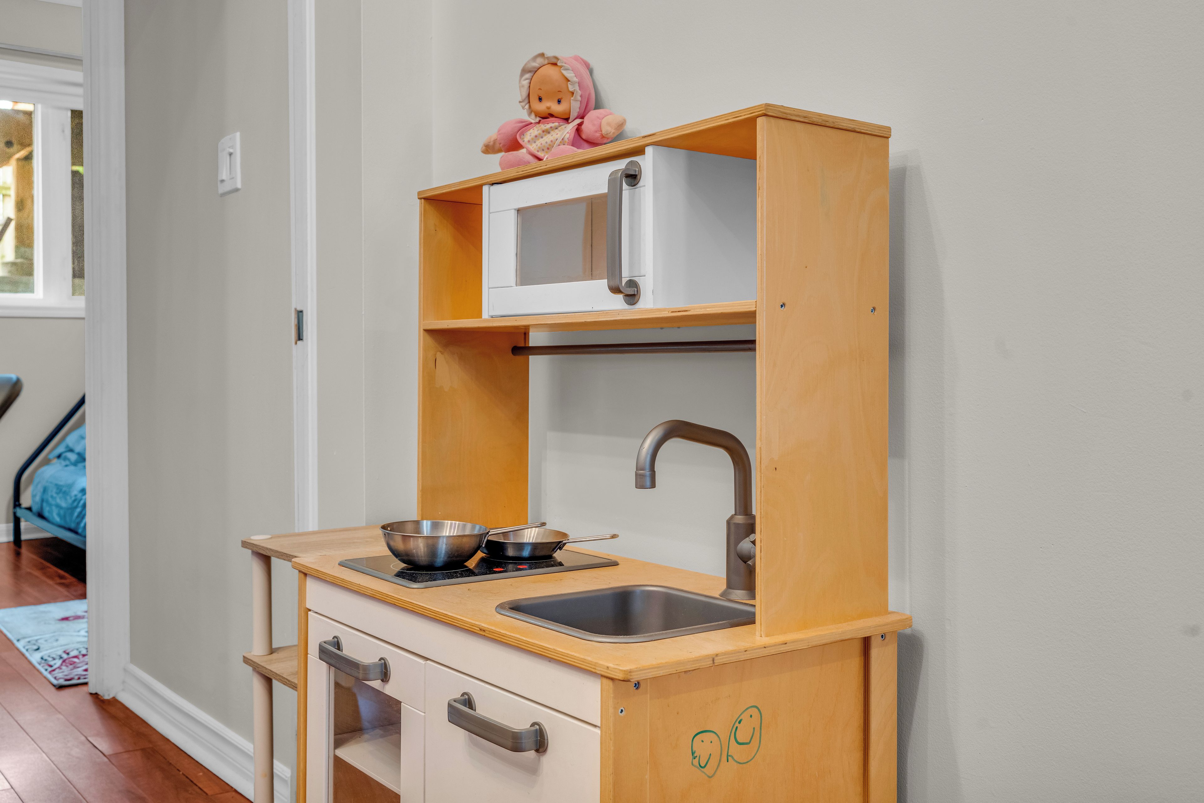 A compact kitchenette with a microwave, sink, and two pots on a stove.