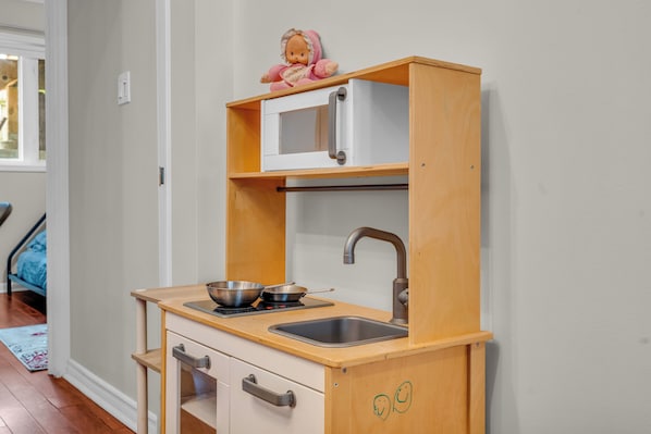 Una kitchenette compacta con microondas, pileta y dos ollas sobre una estufa.