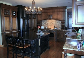 A kitchen with dark wood cabinetry, a central island, a stove, and a chandelier. - Large country home with 4 en suite bedrooms, large living room & chefs kitchen (Amoret)